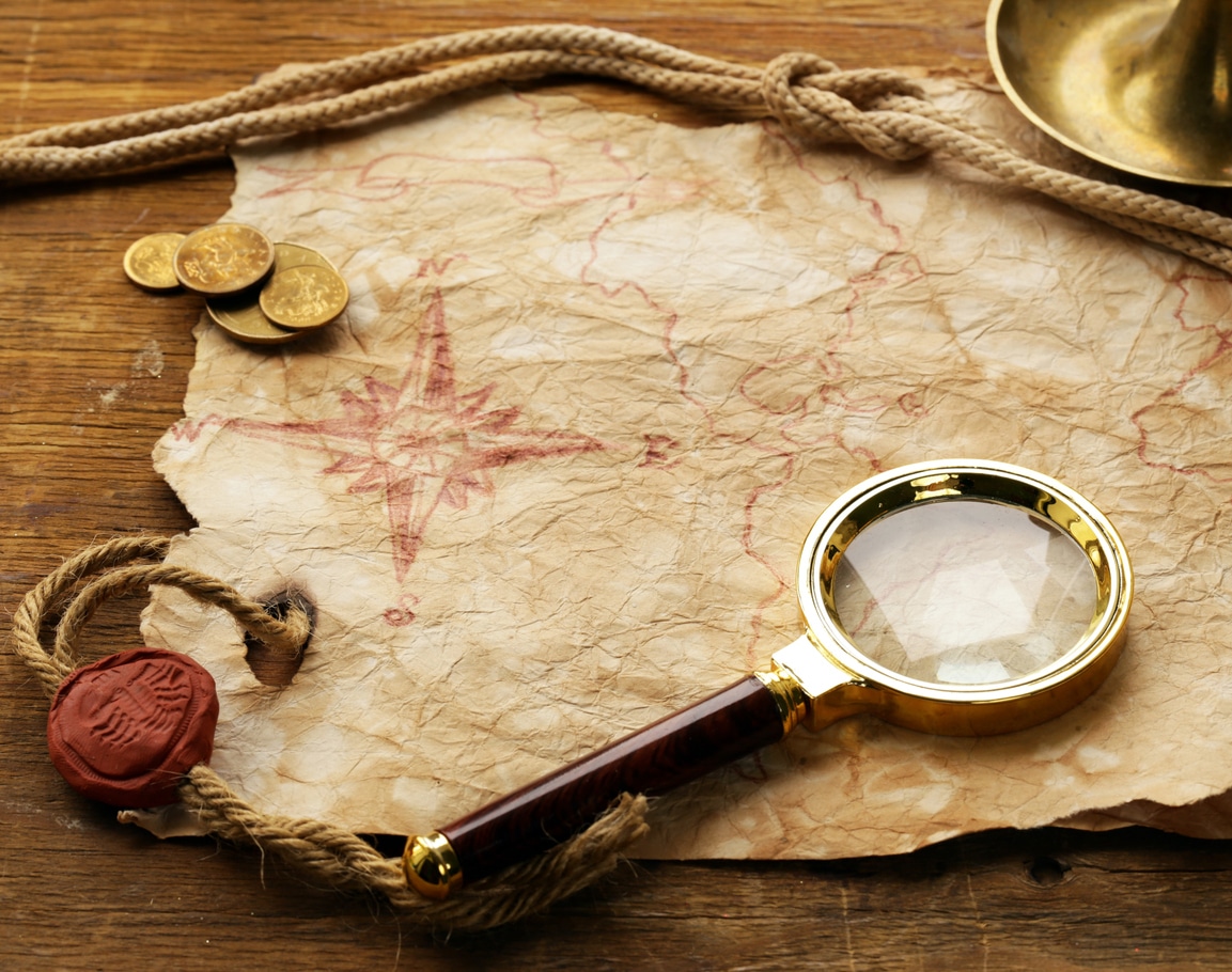 Carte ancienne, boussole rouge, loupe et pièces, prête pour votre aventure escape game à Toulon.
