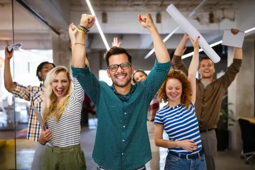 Joueurs en équipe, bras levés, sourires et esprit de team building dans un décor moderne.