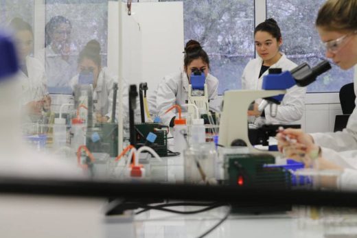 En équipe, manipulez microscopes et verrerie dans un grand laboratoire high-tech, ambiance scientifique immersive.