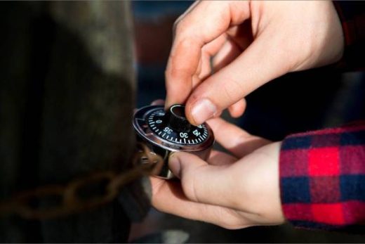 Participant en chemise à carreaux ouvrant un cadenas, prêt pour l'aventure escape game chez Laeris.