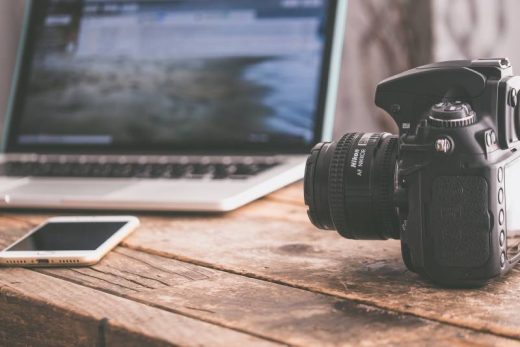 Appareil photo, smartphone et laptop sur une table bois, prêts pour l'aventure ou le team building Laeris.