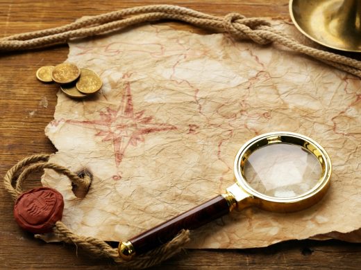Carte ancienne, boussole rouge, loupe et pièces, prête pour votre aventure escape game à Toulon.