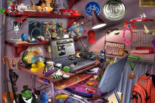 Un bureau chargé d'objets variés : laptop, caméra, globe, jouets, souvenirs et trophées sur étagères.