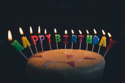 Gâteau d'anniversaire, bougies "HAPPY BIRTHDAY" colorées allumées, parfait pour fête à Toulon.