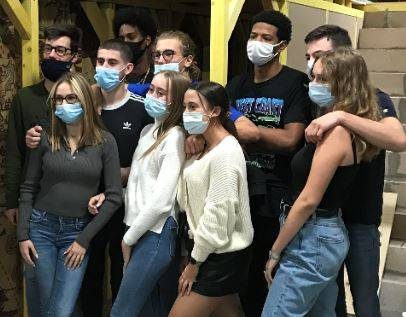 Onze jeunes posent masqués devant des escaliers jaunes, l'esprit Laeris Escape Game à Toulon.