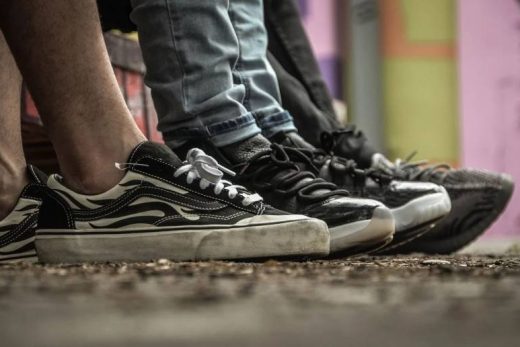 Trois paires de sneakers noires alignées, ambiance urbaine sur sol brut, prêts à relever le défi.