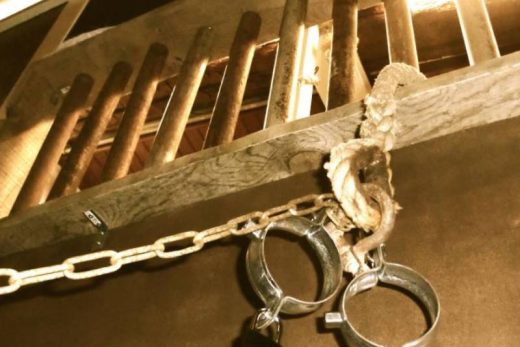 Menottes verrouillées pendent d'une chaîne sous des barreaux, ambiance escape game Toulon Laeris.
