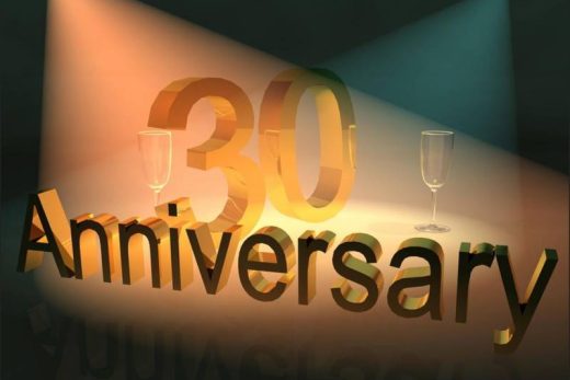 Or "30 ans" et flûtes de champagne sous projecteurs, ambiance festive sur fond sombre.
