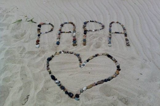 PAPA" écrit et un cœur en galets posés sur le sable, souvenir unique comme nos jeux Toulon.
