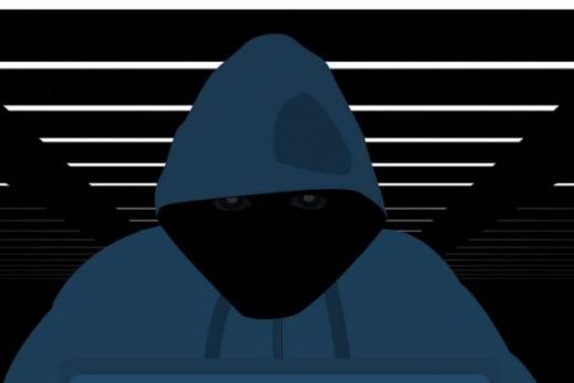 Hoodie-clad individu mystérieux devant un ordinateur, ambiance sombre façon escape game immersif.