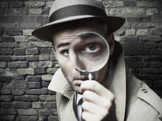 Détective en trench et chapeau scrutant un indice, ambiance escape game Laeris à Toulon.