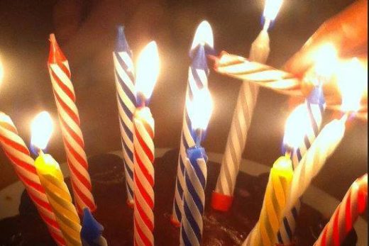 Gâteau au chocolat, bougies multicolores allumées, une main éclaire la dernière-ambiance festive Laeris.
