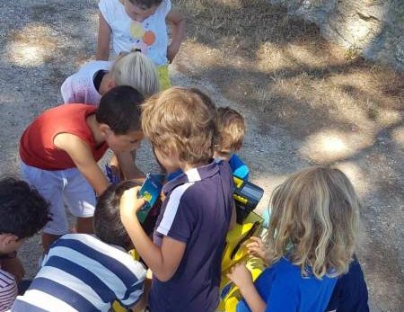 Enfants examinant ensemble une voiture jaune, ambiance ludique, extérieur ensoleillé, activité immersive.