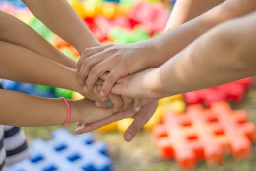 Mains réunies pour un team building Laeris, blocs colorés en arrière-plan.