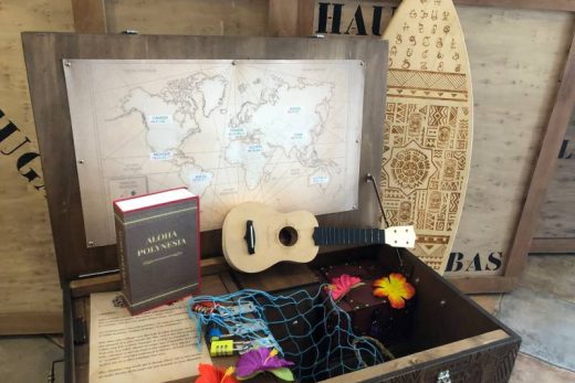Coffre en bois avec carte, ukulélé, fleurs, livre et décor polynésien. Ambiance escape game immersive.