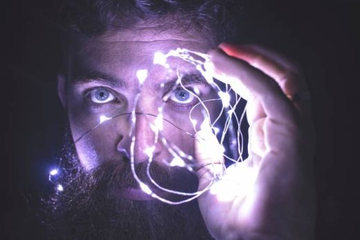 Barbu éclaire son visage avec guirlande lumineuse, ambiance mystérieuse, soirée immersive Laeris Toulon.