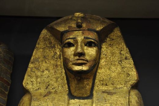 Ancien couvercle de sarcophage égyptien en or, visage stylisé, détails noirs, coiffe-iconique depuis 2016.