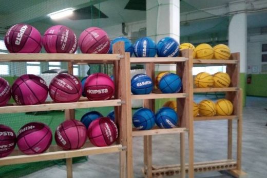 Ballons rose, bleu et jaune sur racks en bois dans gymnase lumineux, ambiance escape game Toulon.