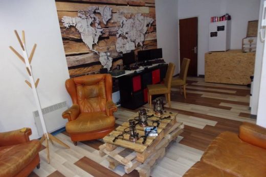 Espace lounge moderne : fauteuils cuir, table palette, carte monde et bureaux bois, ambiance travail immersive.