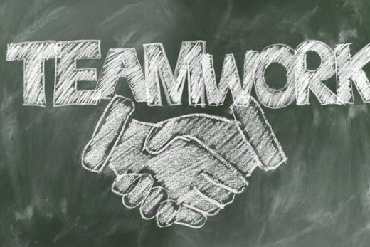 TEAMWORK" en lettres blanches et une poignée de main dessinées à la craie sur tableau noir.