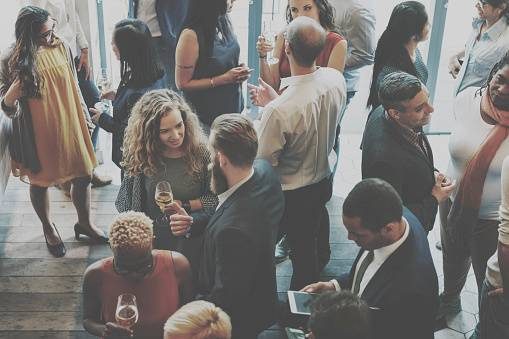 Professionnels discutant autour de verres lors d'un événement convivial en intérieur.