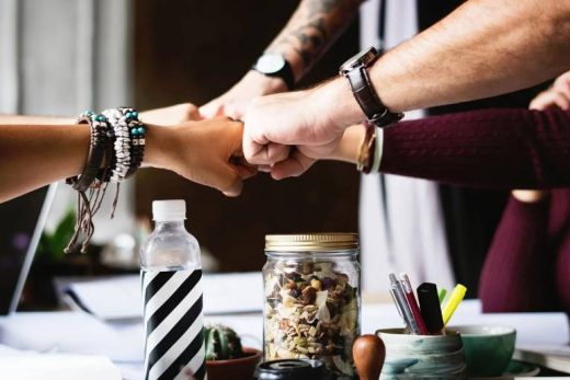 Team building : quatre collègues se félicitent autour d'une table, ambiance conviviale au travail.