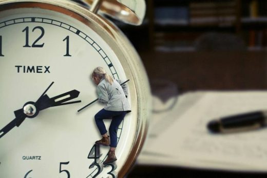 Une petite femme escalade une horloge géante, un bureau flou avec des papiers et un stylo derrière. Scénario immersif, Laeris Toulon.