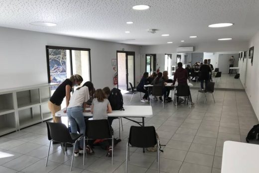 Joueurs réunis autour de tables, dans un espace lumineux et moderne avec grandes fenêtres et sol carrelé.