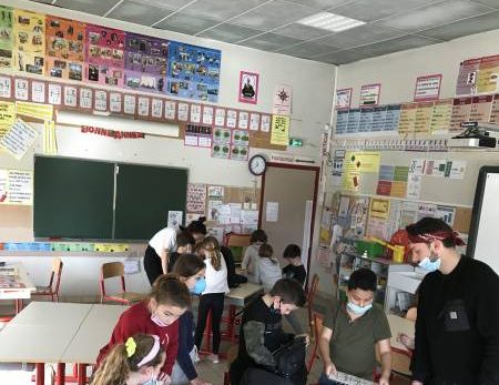 Enfants et adulte résolvent des énigmes dans une salle colorée décorée d'affiches ludiques.