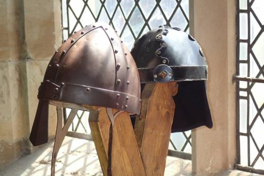 Deux casques médiévaux sur supports bois près d'une fenêtre à carreaux, ambiance escape game Laeris.