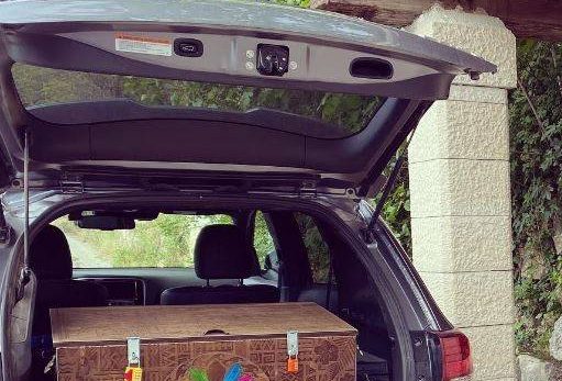 Coffre en bois décoré fermé à clé, prêt pour un scénario mobile Laeris dans le coffre d'un SUV argenté.