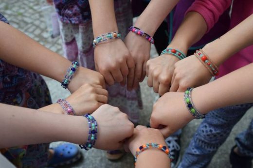 Cercle de mains joyeuses, bracelets colorés, esprit d'équipe ludique et immersif chez Laeris.